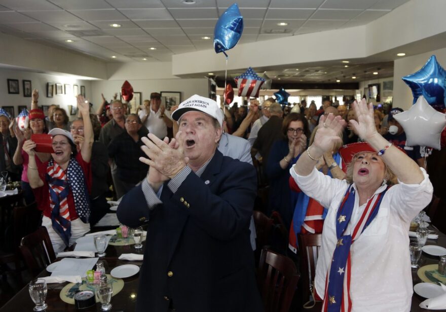 Frank de Varona, left, and Martie Mees, right, applaude as they watch a televised broadcast of the presidential inauguration of Donald Trump, Friday, Jan. 20, 2017, during a watch party organized by Hispanas for Trump in Miami. (AP Photo/Lynne Sladky)