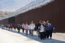  A group of people walk along the wall after crossing the border with Mexico in 2023