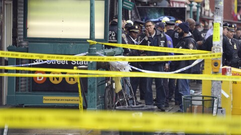 New York City Police Department personnel gather at the entrance to a subway stop in the Brooklyn borough of New York, Tuesday, April 12, 2022. Multiple people were shot and injured Tuesday at a subway station in New York City during a morning rush hour attack that left wounded commuters bleeding on a train platform.