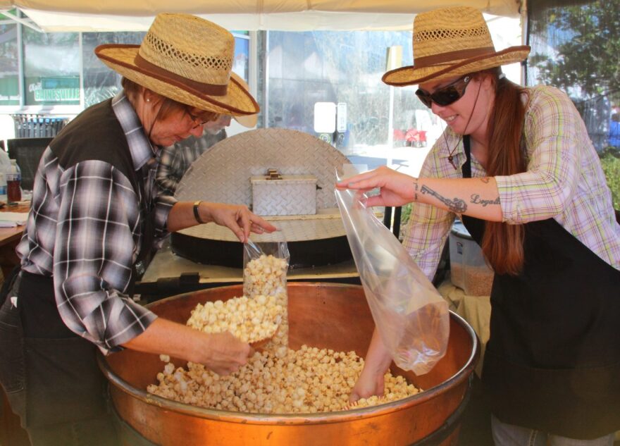 Kathy Dunham and Laura Theus scoop fresh kettle corn into bags. Dunham has been a regular at the festival for the past decade. (Photo by Kayla Ziadie)