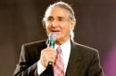 man in dark suit talks behind a podium with a microphone