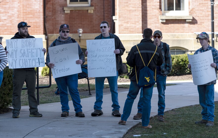 A group of counter-protesters stand next to a group of protesters near Martin Hall on WVU's downtown campus on Thursday, Feb. 21, 2019, during a faculty and student demonstration over proposed campus concealed firearms carry legislation.