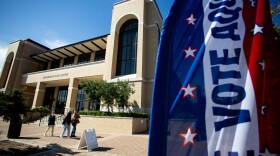 A flag in front of a Texas State University building says "Vote."