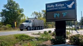A dump truck drives past Holly Ridge Elementary School in Holly Ridge, Louisiana, on Friday, October 17, 2025. The school is less than a mile away from the construction site of Meta’s new data center, Hyperion. Officials shut down the playground in front of the school because of safety concerns related to the truck traffic.