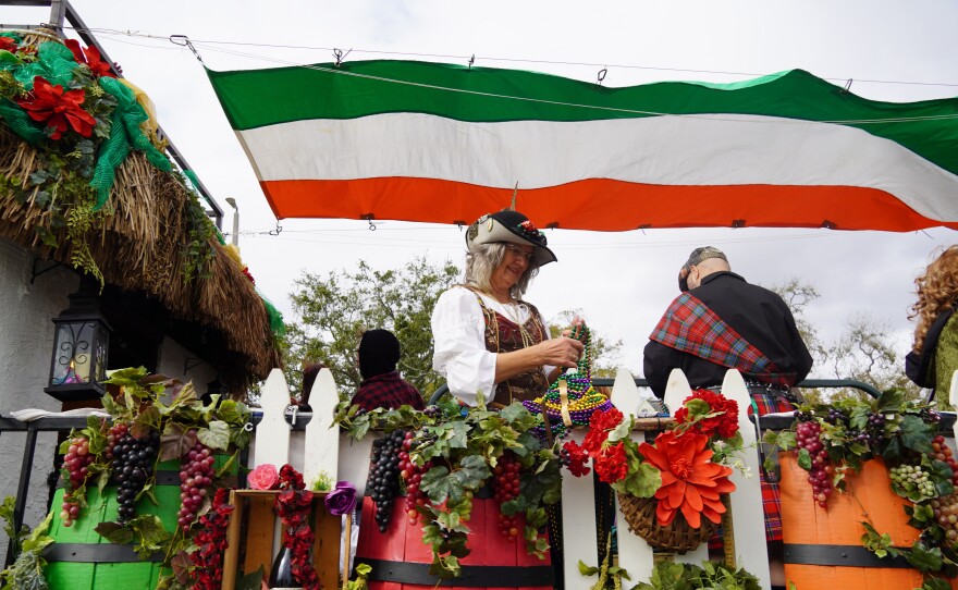 Fruit on a parade float with woman holding colorful beads 