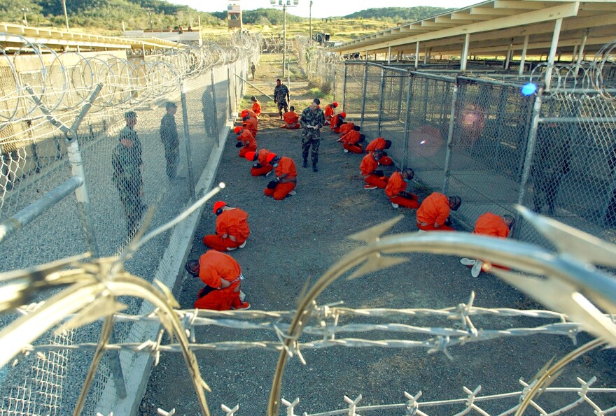 In this handout photo provided by the U.S. Navy, U.S. Military Police guard detainees in orange jumpsuits on Jan. 11, 2002 at Guantánamo Bay, Cuba.