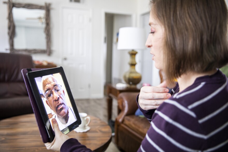 A woman talks to her healthcare provider on a tablet.