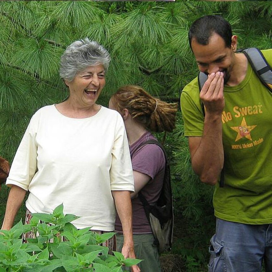 Lucille Bertuccio Laughs as Ross Gay sniffs bee balm leaves in a Wild Edibles workshop she led, through Mother Hubbard's Cupboard (~2012). Lucille passed away in 2016.