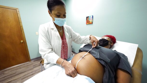 Dr. Felecia Brown, a midwife at Sisters in Birth, a Jackson, Miss., clinic that serves pregnant women, left, measures the stomach of Kamiko Farris of Yazoo City, Miss., Dec. 17, 2021. The clinic utilizes an integrative and holistic approach to women's healthcare by providing comprehensive services including primary care, midwifery care, home healthcare, childbirth education as well as doula support. (AP Photo/Rogelio V. Solis)