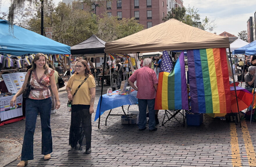 Two friends smile as they walk past the different vendors at the Gainesville Pride festival on Saturday, Oct 3, 2026. (Madison Middleton/WUFT News)