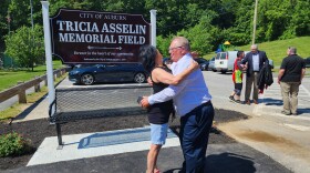 Bobbi Nichols, sister of Tricia Asselin, gets a hug from Leroy Walker, father of Joe Walker, in front of the ballfield now named for Asselin. Asselin and Walker were two of the 18 people killed in the Lewiston mass shootings last October.