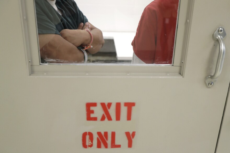 A view of two people through a glass window of a door that reads "exit only."