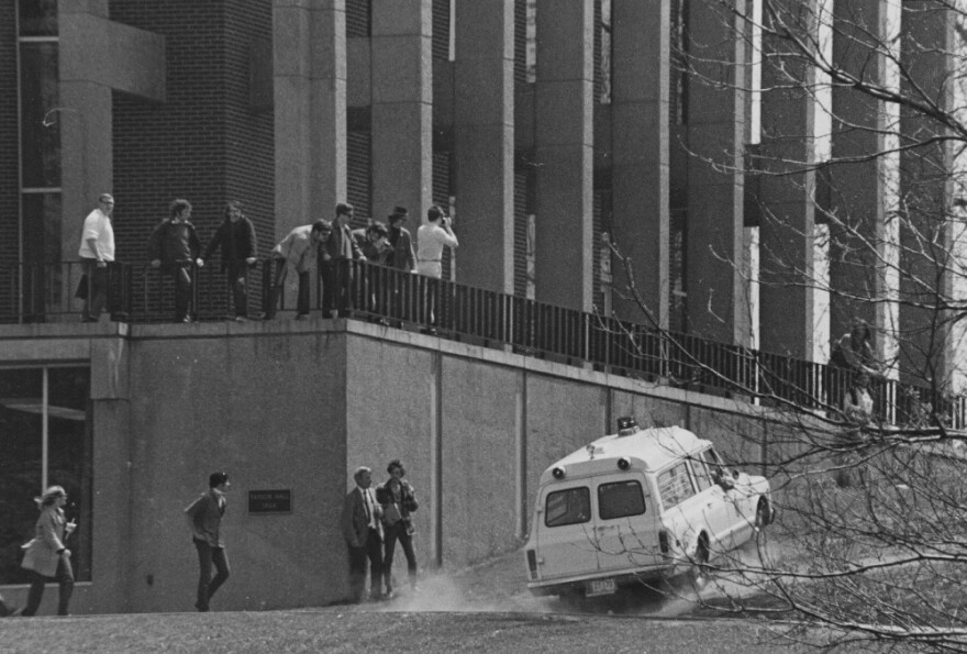 Ambulance drives over the grass on commons to Taylor Hall rushing to wounded students on the other side.