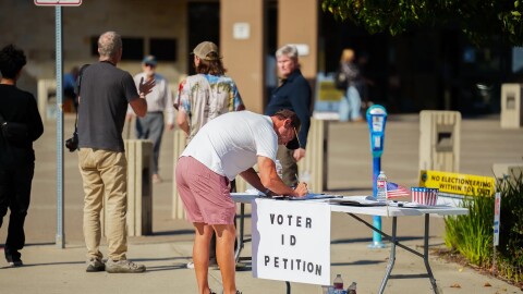 A person signs one of several different petitions at a vote center at the Huntington Beach Central Library in Huntington Beach on Nov. 4, 2025.