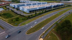 FILE - Cars drive past data centers that house computer servers and hardware required to support modern internet use, such as artificial intelligence, in Ashburn, Virginia, July 16, 2023.