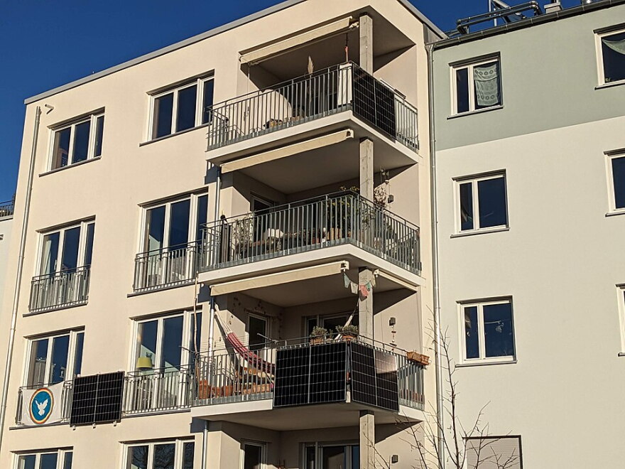 Image shows the small, portable plug-in solar panels hanging off an apartment balcony 