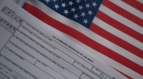 A form for a birth certificate laying on top of a small American flag.