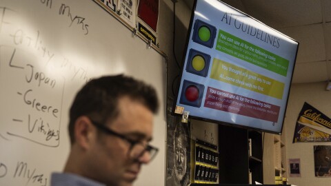 English teacher Casey Cuny reads in his classroom as a screen displays guidelines for using artificial intelligence at Valencia High School in Santa Clarita, Calif., Wednesday, Aug. 27, 2025.