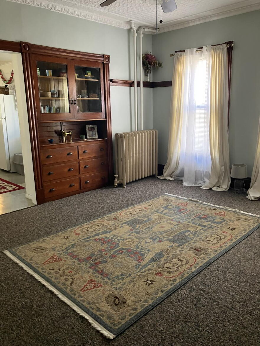 A photo of a living room with a window and carpet.