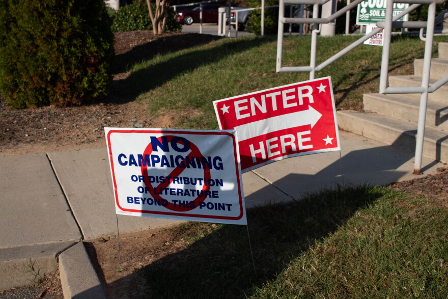 Two signs outside of a polling location which say "No campaigning" and "Vote here"