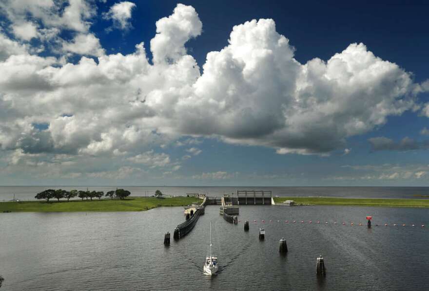 In this Friday, Oct. 25, 2019, photo, a sailboat starts down the St. Lucie Canal after leaving Lake Okeechobee, background, through the Port Mayaca, Fla., lock north of Belle Glade, Fla. The lock and dam was built in 1977 to raise the water level in the lake and provide flood control. (AP Photo/Robert F. Bukaty)