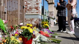 People stand at a makeshift memorial near the scene of the shooting.