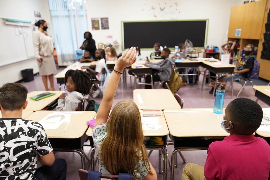 A student raises their hand in a classroom. 