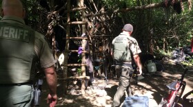 Jackson County Sheriff's deputies walk through a years-old encampment hidden near the Bear Creek Greenway outside Medford, an elaborate set of structures that deputies call "the Hobbit House."
