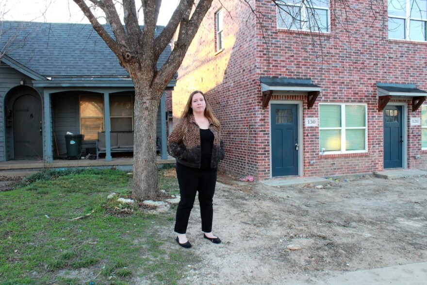 A woman stands outside in her yard.