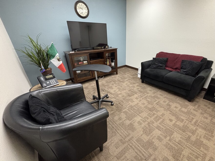 A room with a chair and a couch on opposite ends.