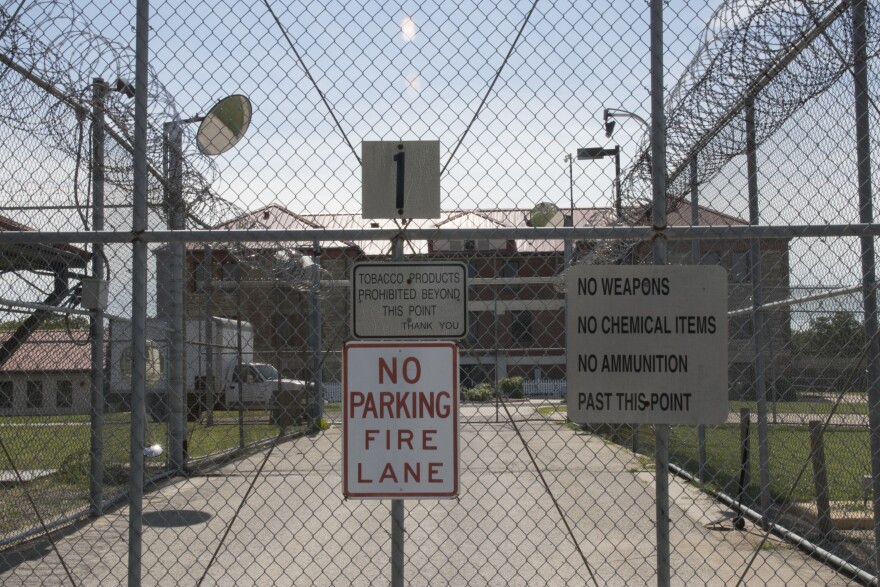 Signs telling people no tobacco, parking or weapons or allowed. The signs are on the chainlink fence outside a state prison.