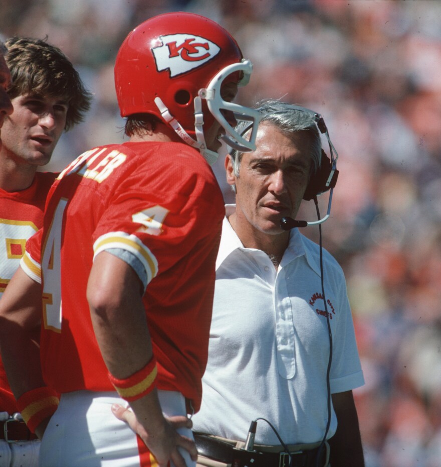 Former Kansas City Chiefs head coach Marv Levy talks to Kansas City Chiefs quarterback Steve Fuller (foreground) and Bill Kenney (background) on the sidelines during a 1979 NFL football game.