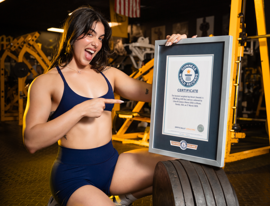Lilian Zamora Alonso posing with the Guiness World Record certificate for heaviest weighted hip thrust by a woman.