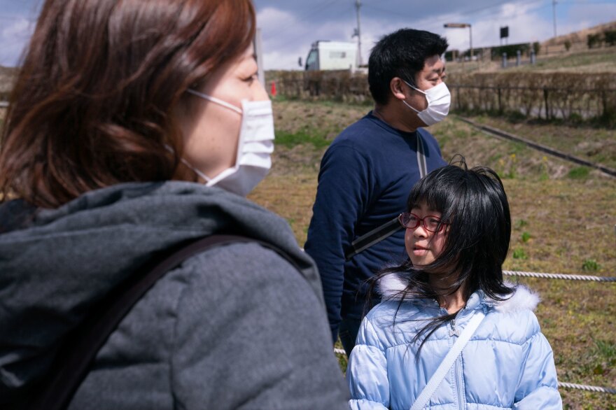 Kazue Otomo (left) and Kenjiro Otomo with their older daughter Ana, 9, visit the tree one last time before they move away from the area.