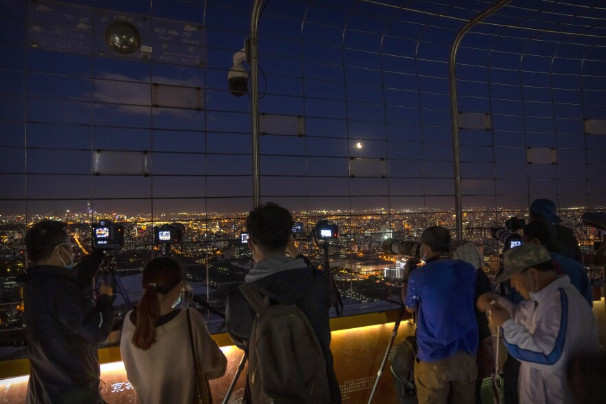 Photographers take photos of a lunar eclipse at the Central TV Tower in Beijing.