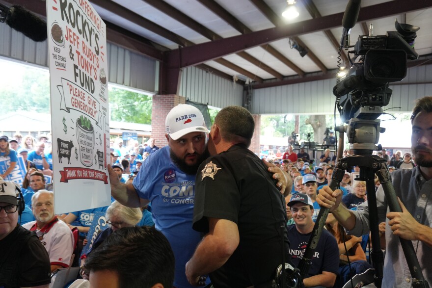 A local sheriff's deputy talks to a persistent shouter about the new policy aimed at stopping chants that simply drown out political speakers.