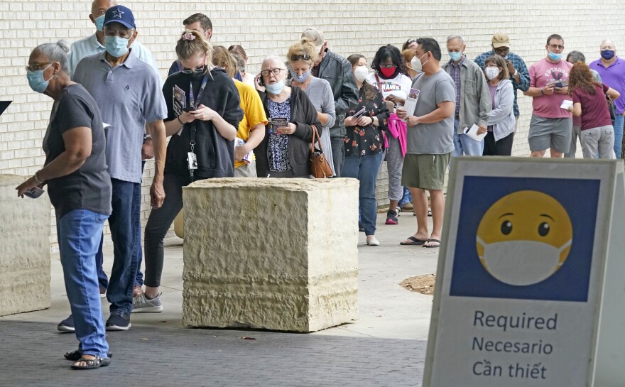 Wearing masks to prevent the spread of COVID-19, voters line up to cast their ballot during early voting Tuesday, April 27, 2021, in Mansfield, Texas.