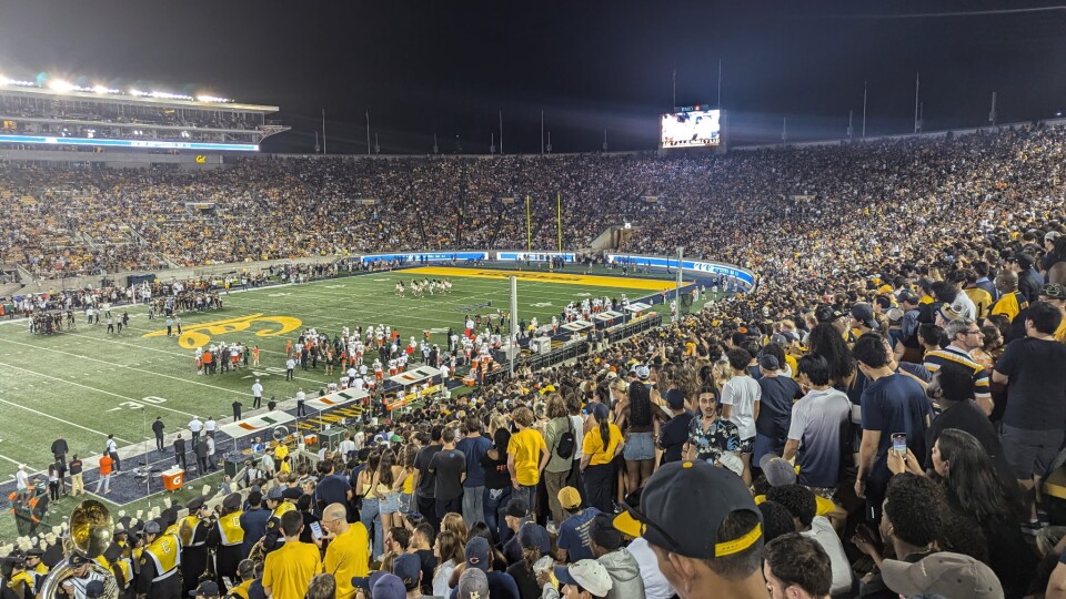 Cal fans wearing blue and gold fill the stadium at Berkeley for an evening football game.