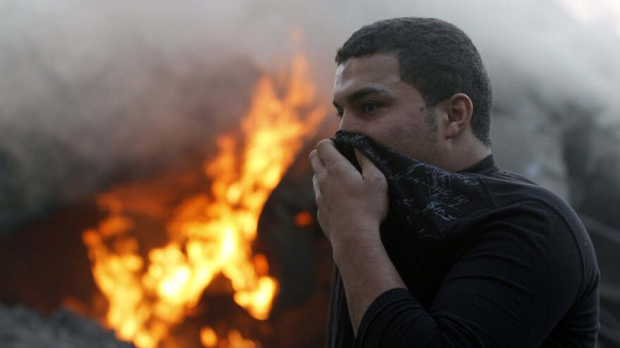 A man covers his face as he passes smoke and fire after Israeli air strikes in Gaza City earlier today.