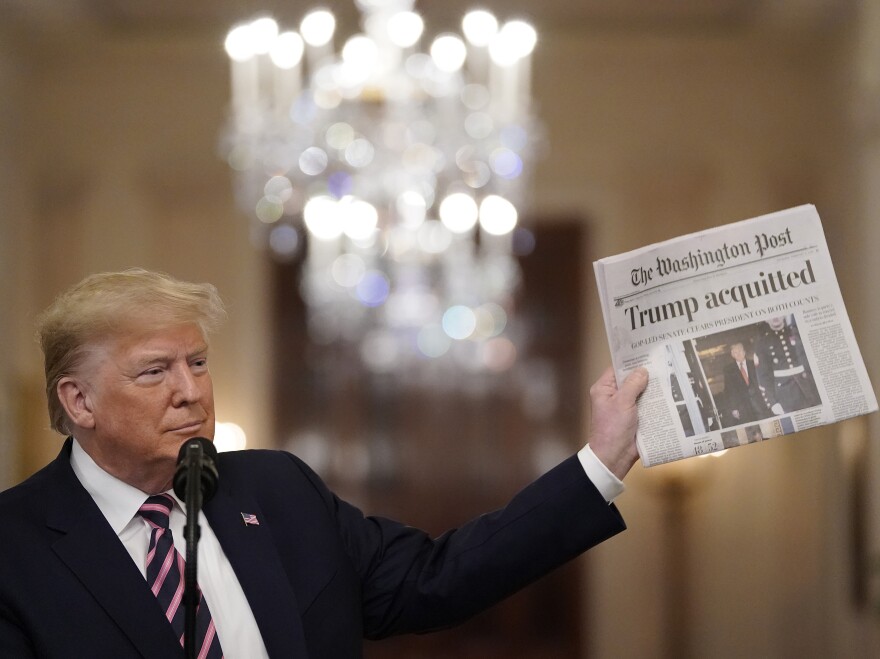 President Donald Trump holds a copy of The Washington Post as he speaks in the East Room of the White House one day after the Senate acquitted on two articles of impeachment in 2020.