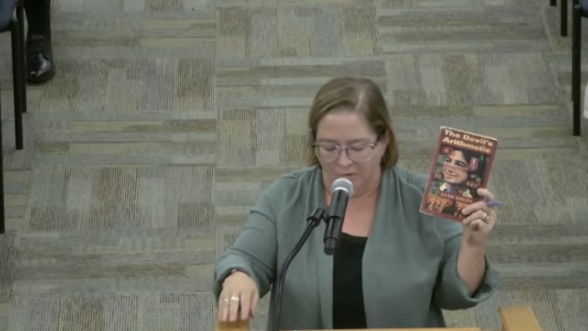 ECPS teacher LeeAnn Eubanks holds a copy of "The Devil's Arithmetic" at the Oct. 20 school board meeting.