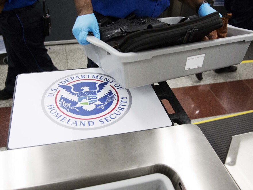 A U.S. Department of Homeland Security seal is seen as a TSA official moves a bin for additional screening at Hartsfield-Jackson Atlanta International Airport.