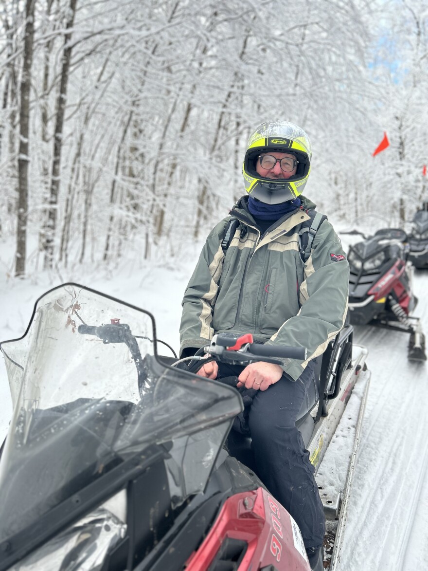 A man in a helmet sits on a snowmobile.