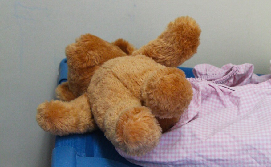 A teddy bear on a cot.