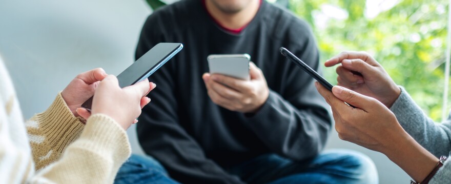 Group of young people using and looking at mobile phone together