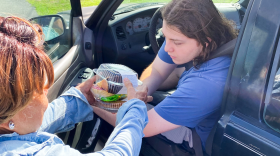 A volunteer with Wings of Faith Fellowship Church in Silver Springs Shores hands pastries to Conner Ortiz during a food distribution at the church last month.
