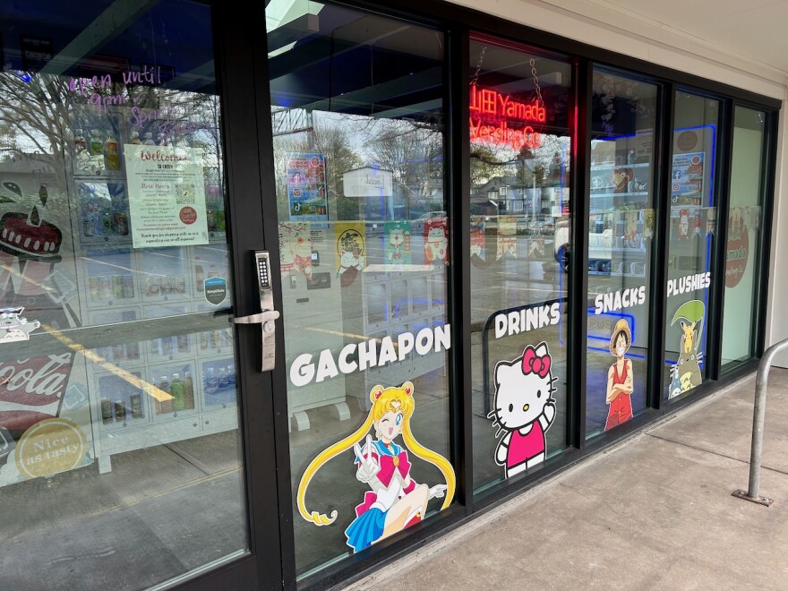A storefront advertising gachapon, drinks, snacks and plushies