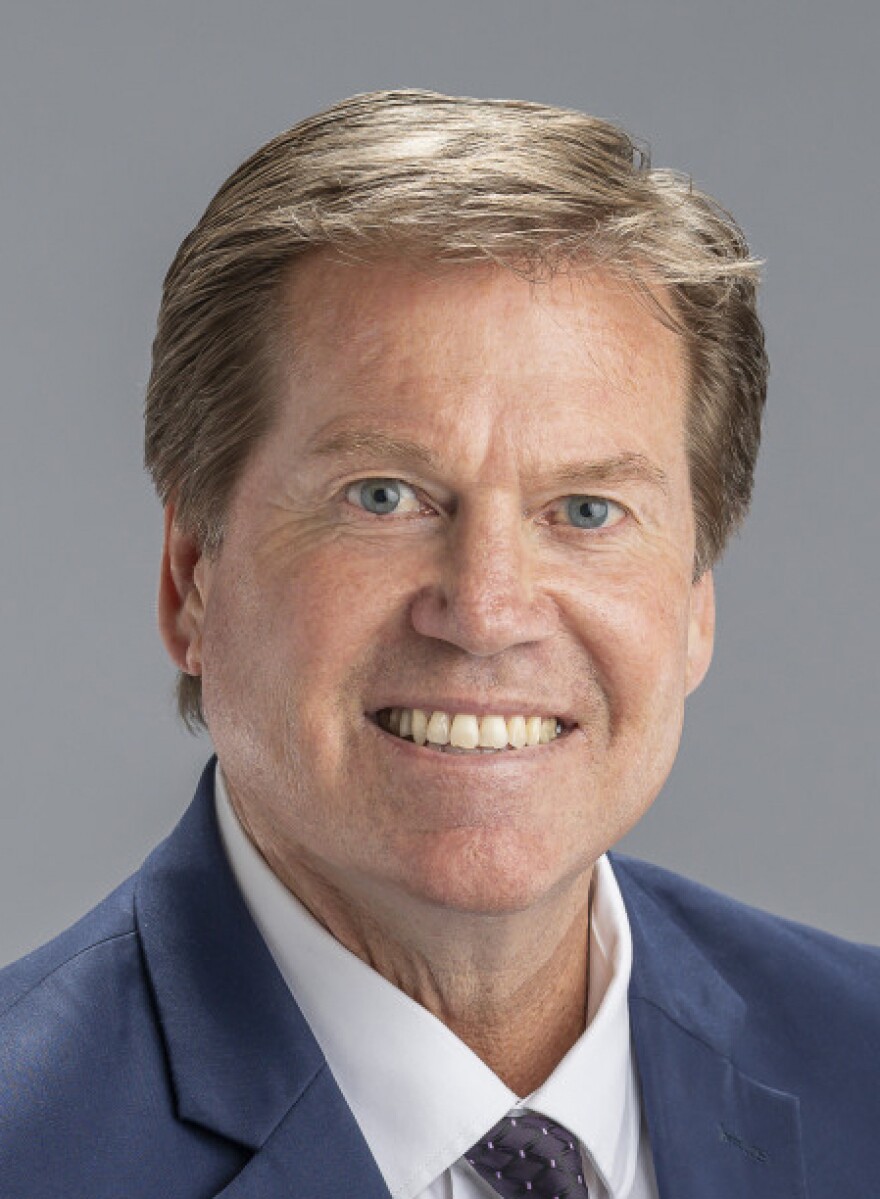A portrait of a man in a shirt and tie with a blue jacket. 