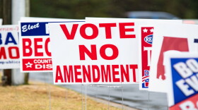 A series of election yard signs with the center one reading "Vote No Amendment"