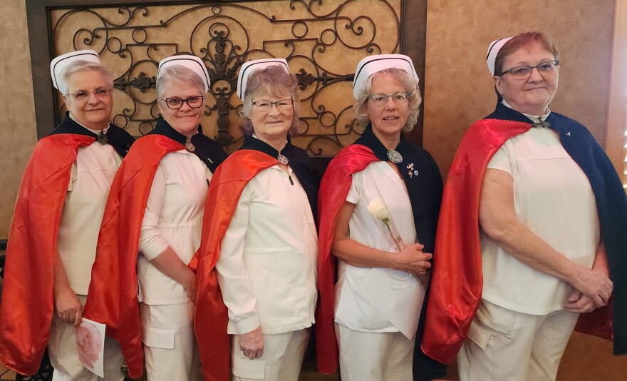 Members of the North Dakota Nurse Honor Guard stand in formation, wearing traditional white uniforms, capes and caps, as they prepare to honor a fellow nurse.